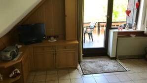 A compact kitchen with wooden cabinets, a small countertop, and a television. - Ferienwohnung Markus (Schmallenberg)