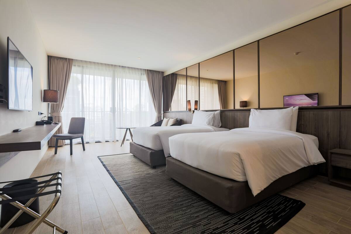 Une chambre d’hôtel moderne, dotée d’un grand lit, d’un bureau et d’une chaise.