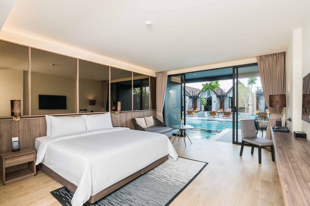 Une chambre d’hôtel moderne dotée d’un grand lit, d’une télévision, d’un bureau et offrant une vue sur une piscine extérieure.