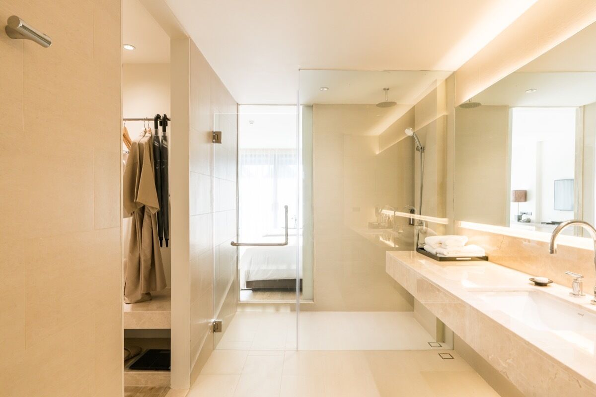 A modern bathroom with a glass shower enclosure, a large mirror, and a vanity with a sink.