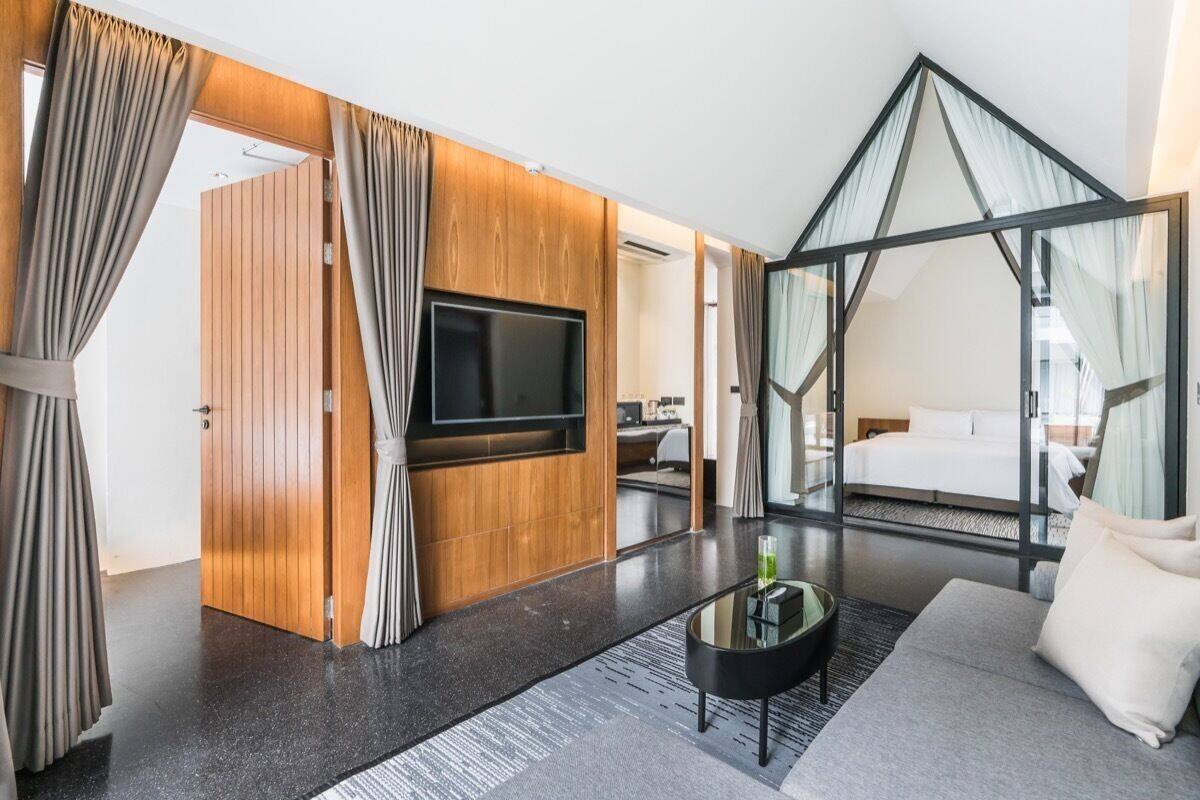Une chambre d’hôtel moderne dotée d’une grande télévision, d’un canapé et d’une cloison en verre.