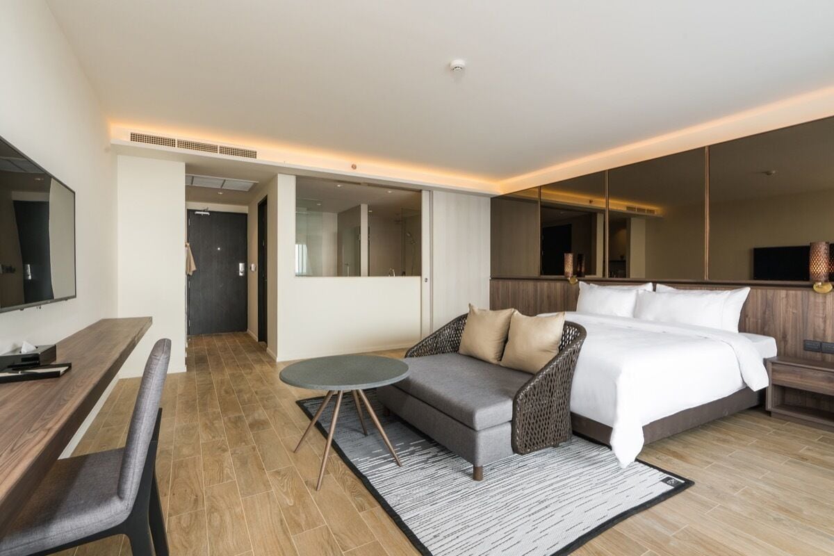 Une chambre d’hôtel moderne avec un grand lit, un canapé, une table à manger et un téléviseur.
