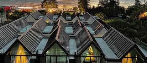 Ein Resort mit mehreren Gebäuden, einem Swimmingpool und Blick auf das Meer bei Sonnenuntergang.