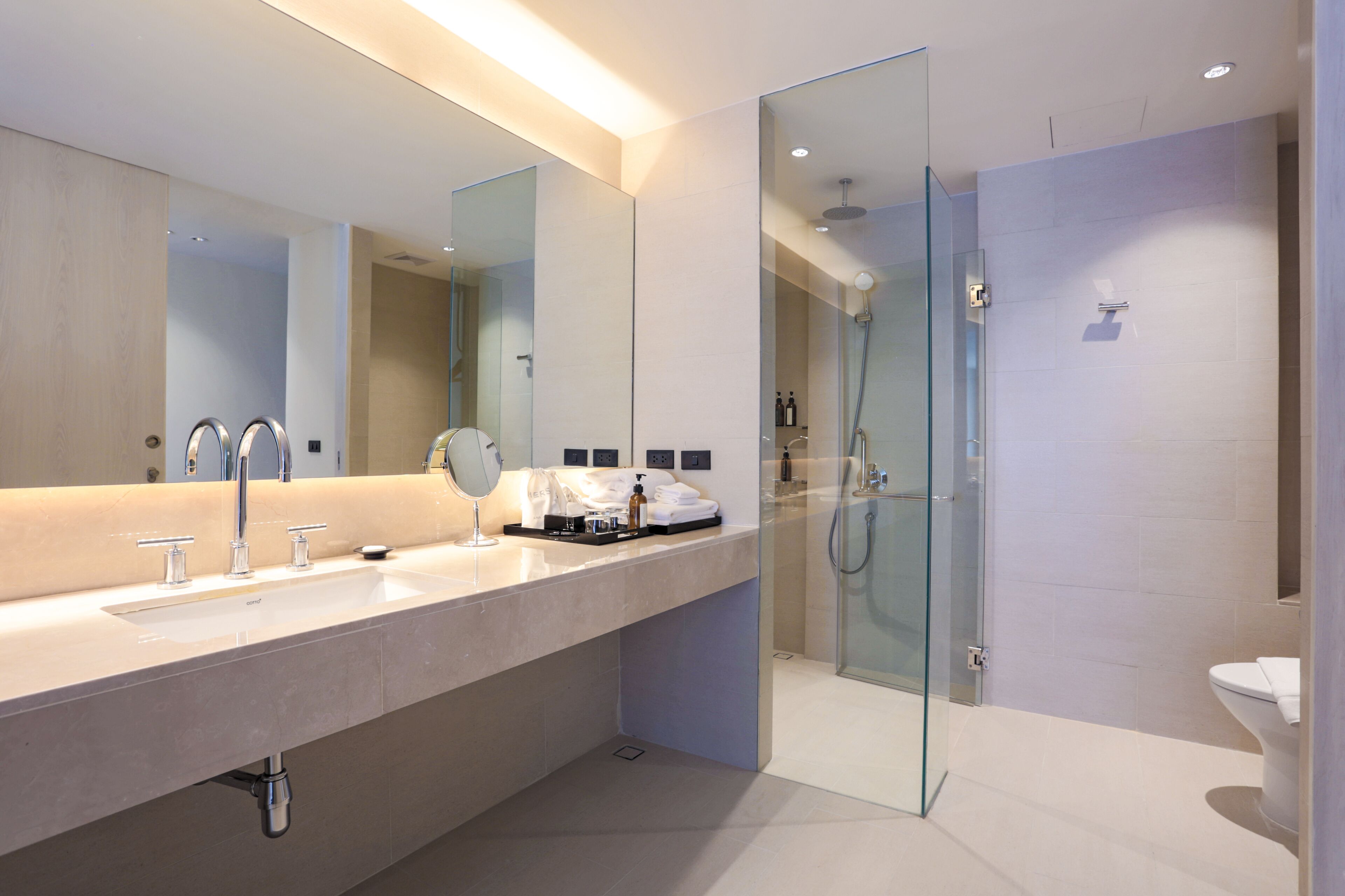 A modern bathroom with a large sink, mirror, and glass shower enclosure.