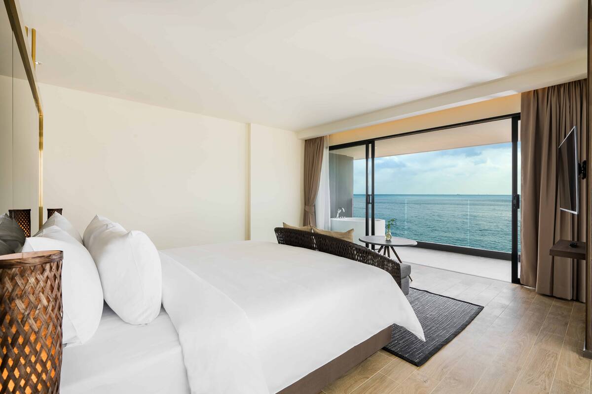 Une chambre d’hôtel moderne avec un grand lit, une vue sur la mer et un balcon.
