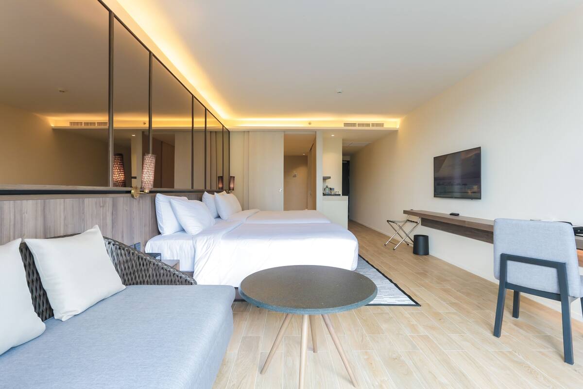 Une chambre d’hôtel moderne équipée d’un lit, d’un canapé, d’une petite table et d’un téléviseur.