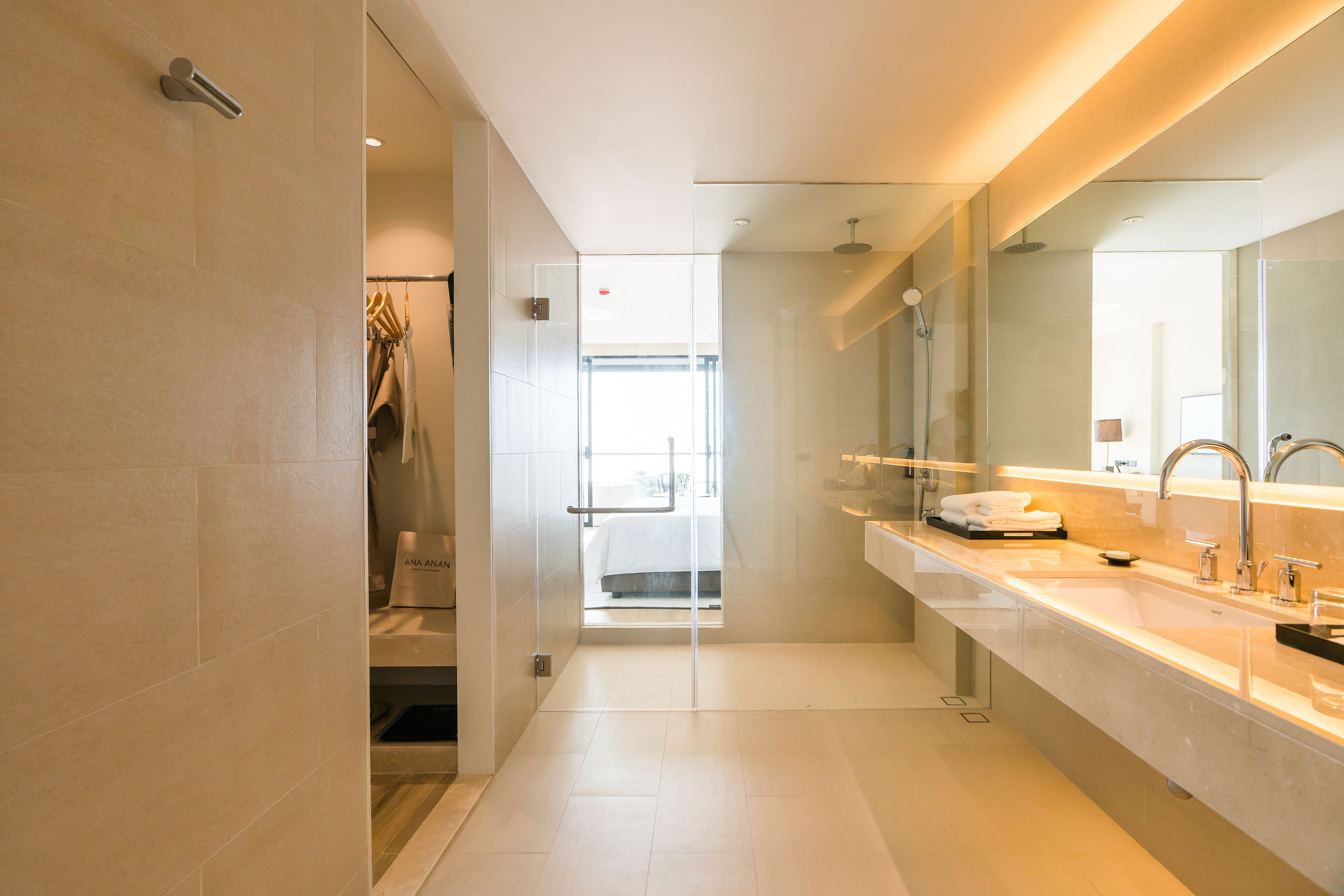 A modern bathroom with a large mirror, two sinks, and a glass shower enclosure.