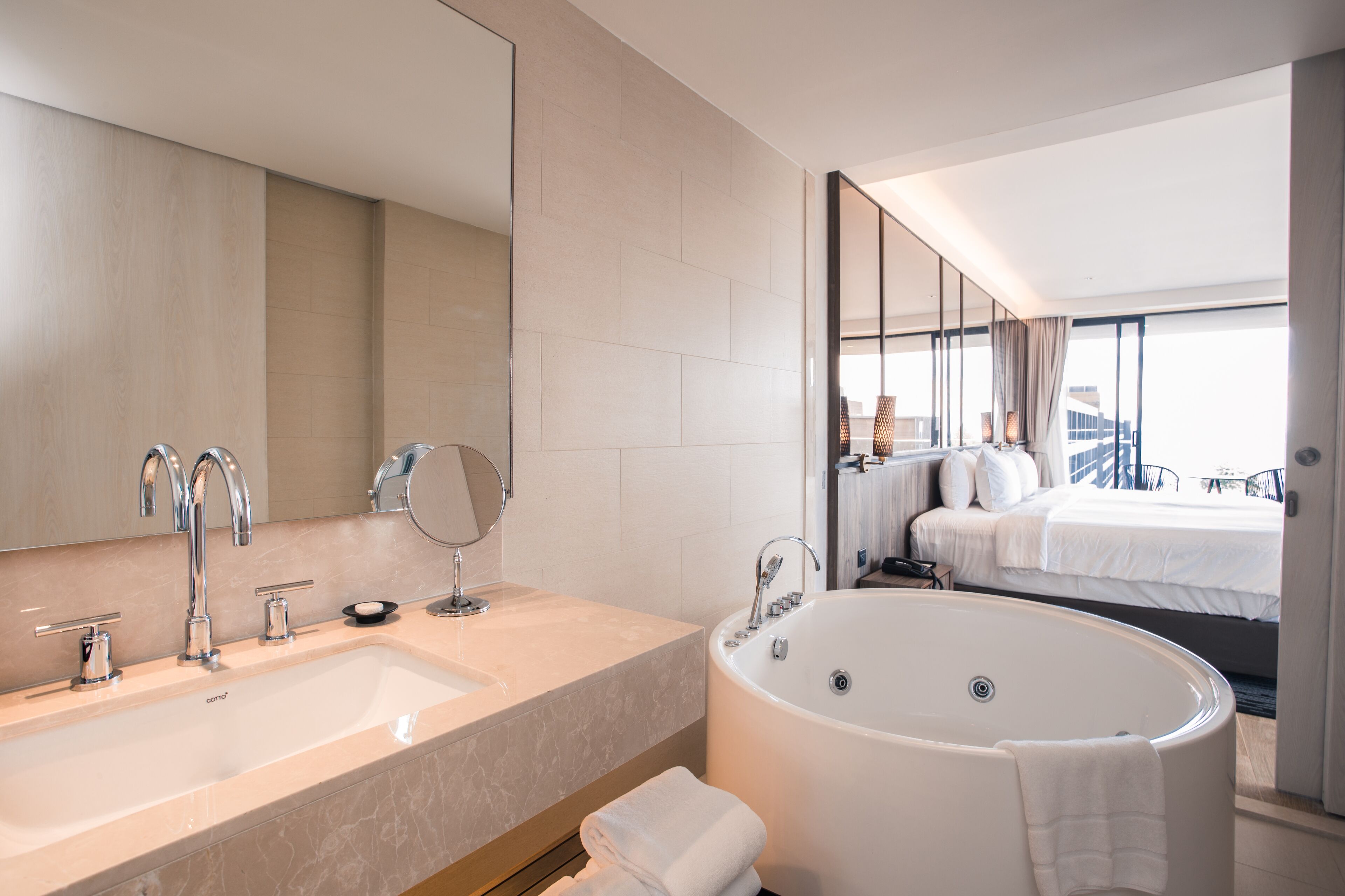 A modern bathroom with a large bathtub, a double sink, and a large mirror.