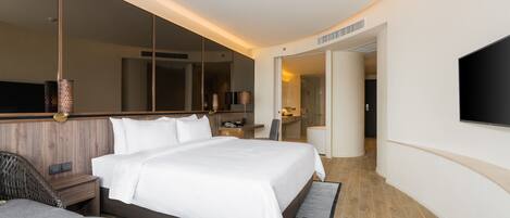 A modern hotel room with a large bed, a flat-screen TV, a desk, and a mirror.