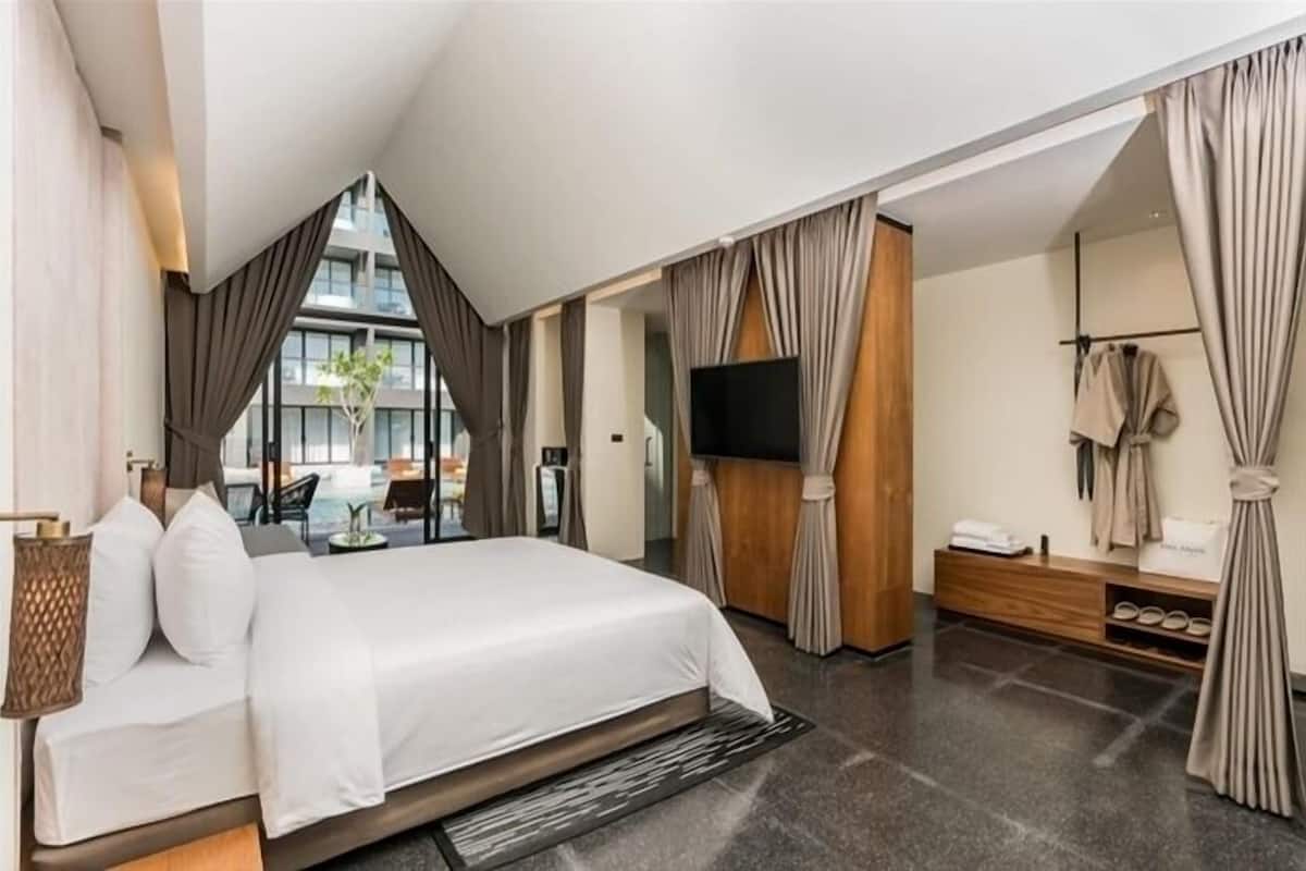 Une chambre d’hôtel moderne dotée d’un grand lit, d’une télévision, d’un coin salon avec vue sur l’extérieur et d’un porte-chaussures.