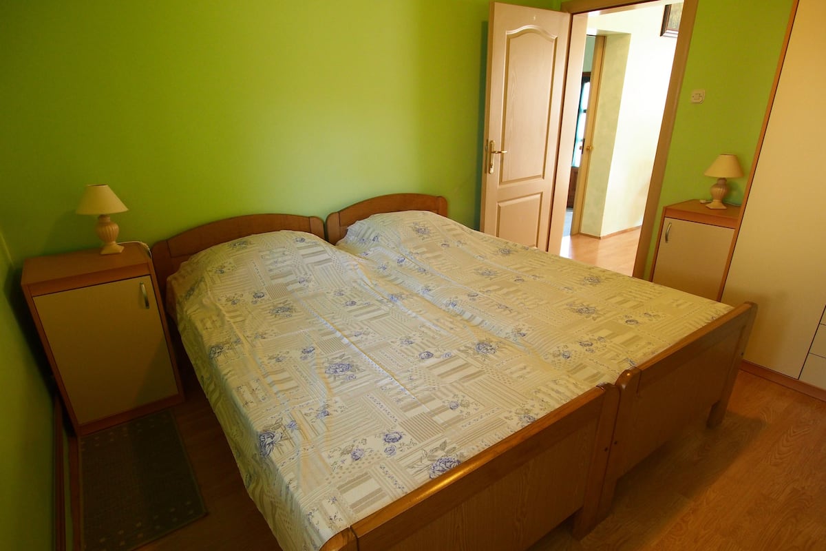 Un dormitorio con una cama doble, dos mesitas de noche, un armario y un espejo.