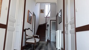 Un couloir avec un sol à carreaux, un escalier et un radiateur.