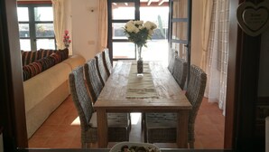 A dining area with a wooden table, wicker chairs, and a sofa.