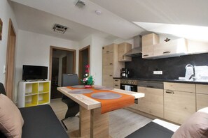 Un espace de vie compact comprenant un coin cuisine, un coin repas et un coin salon.