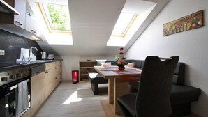 Een moderne keuken met dakramen, een eetgedeelte met tafel en stoelen, en een gezellige zithoek.