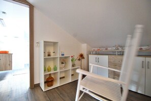 A modern kitchen with white cabinetry, a wooden floor, and a white chair.