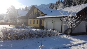 Een gebouw bedekt met sneeuw, met een gele gevel, een garage en een trap die naar de ingang leidt.