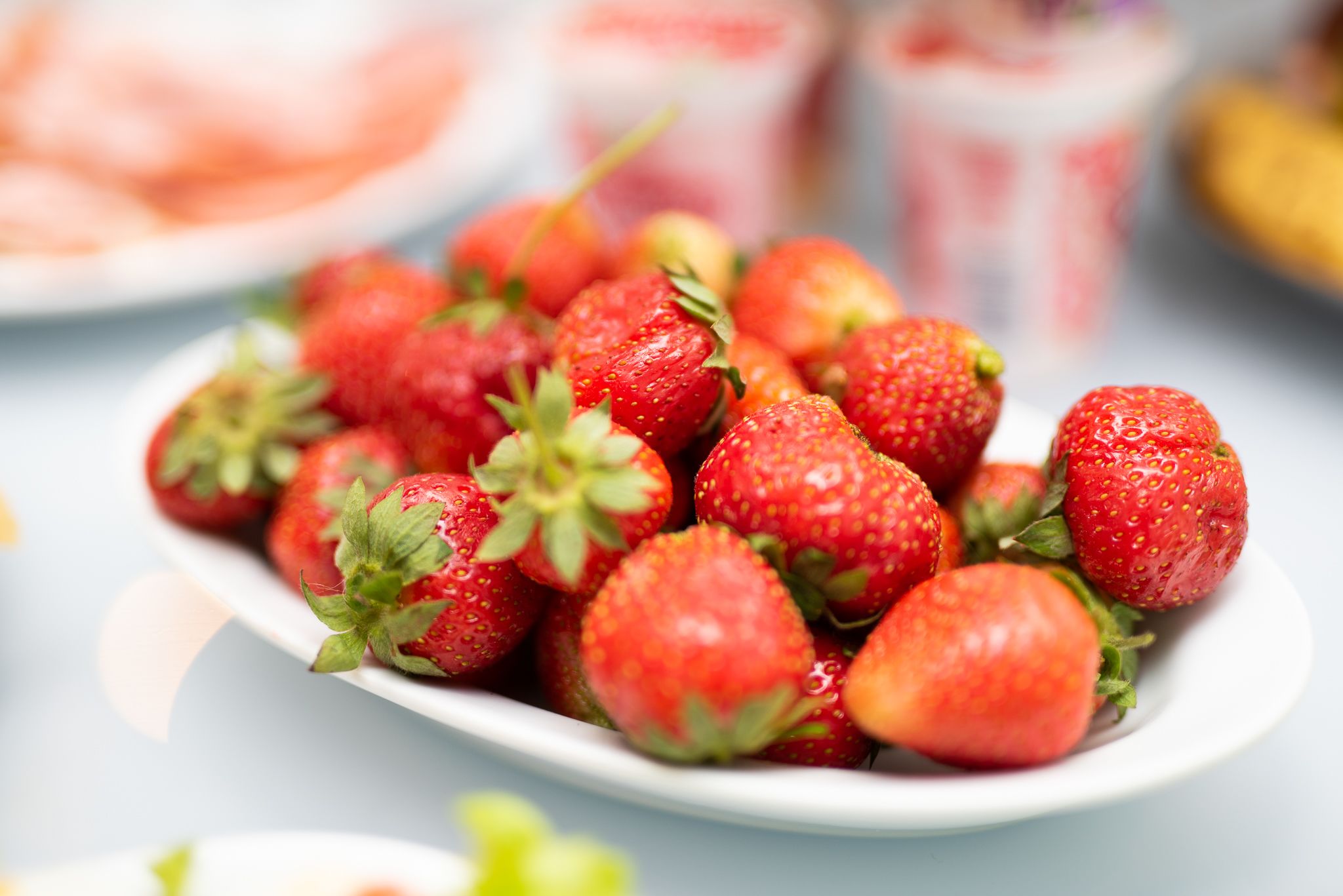 Une assiette blanche remplie de fraises fraîches.