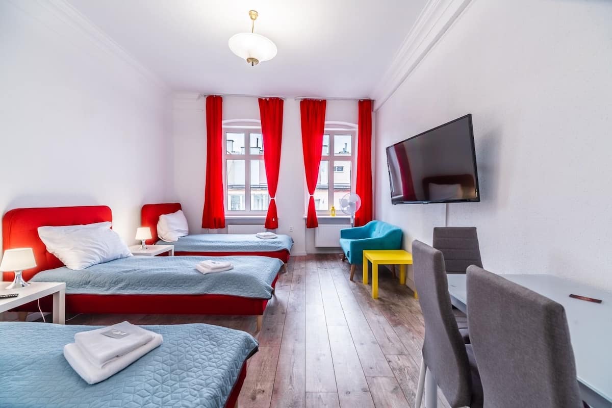 A hotel room with two beds, a TV, a desk, and a chair.