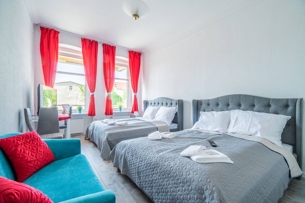 A hotel room with two beds, a sofa, and a desk.