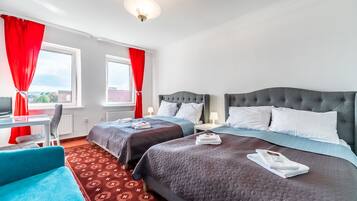 Hotellihuone, jossa on kaksi sänkyä, työpöytä ja tuoli.