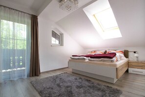 Une chambre avec un puits de lumière, un lit, une table de chevet et une fenêtre avec des rideaux.