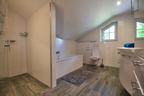 Une salle de bain équipée d’une douche, d’une baignoire, de toilettes et d’une fenêtre.