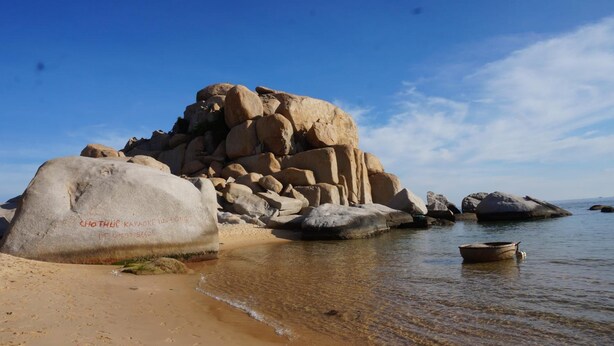 Une plage avec de gros rochers et une eau claire et peu profonde.