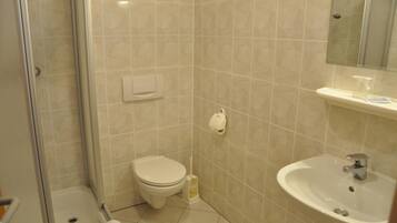 A bathroom with a toilet, sink, and shower.
