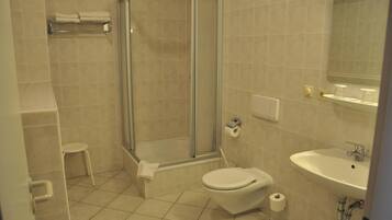 A bathroom with a glass-enclosed shower, a toilet, and a sink.