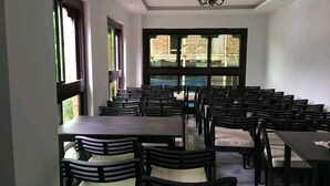 Une salle avec plusieurs tables et chaises disposées pour les repas.