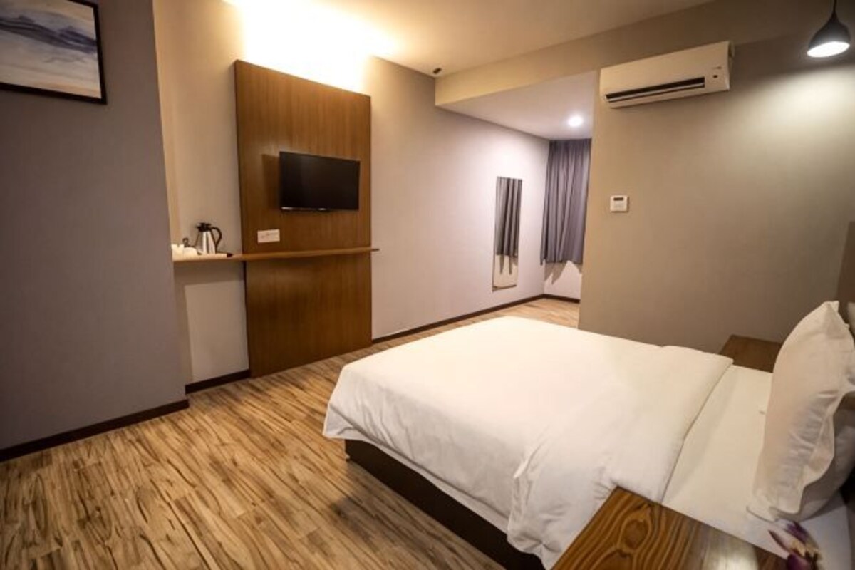 Una habitación de hotel con una cama, televisión, aire acondicionado y suelo de madera.