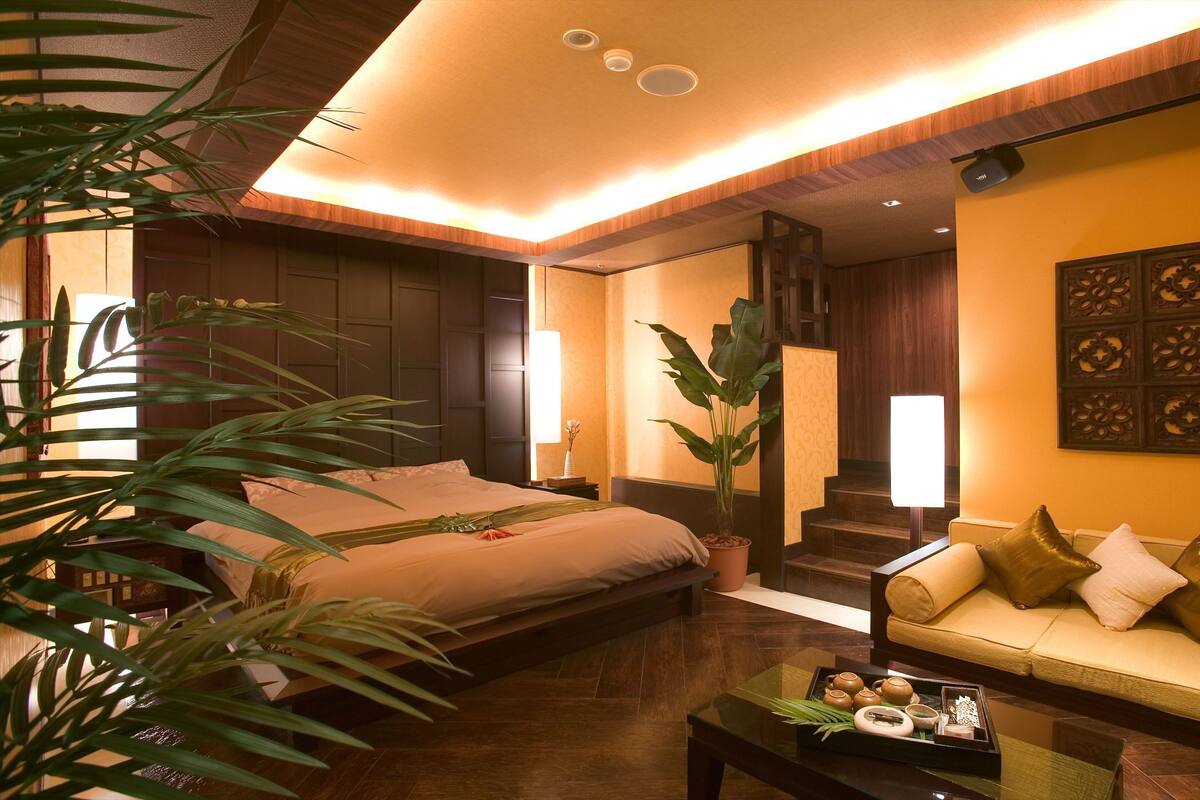 A hotel room with a bed, a sofa, a coffee table, and a large plant.