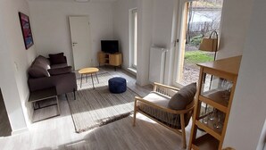 Ein Wohnzimmer mit Sofa, Hocker, TV-Stand und einem Sessel.