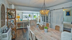 Een ruime eetruimte met een houten tafel, stoelen en een decoratieve kroonluchter.