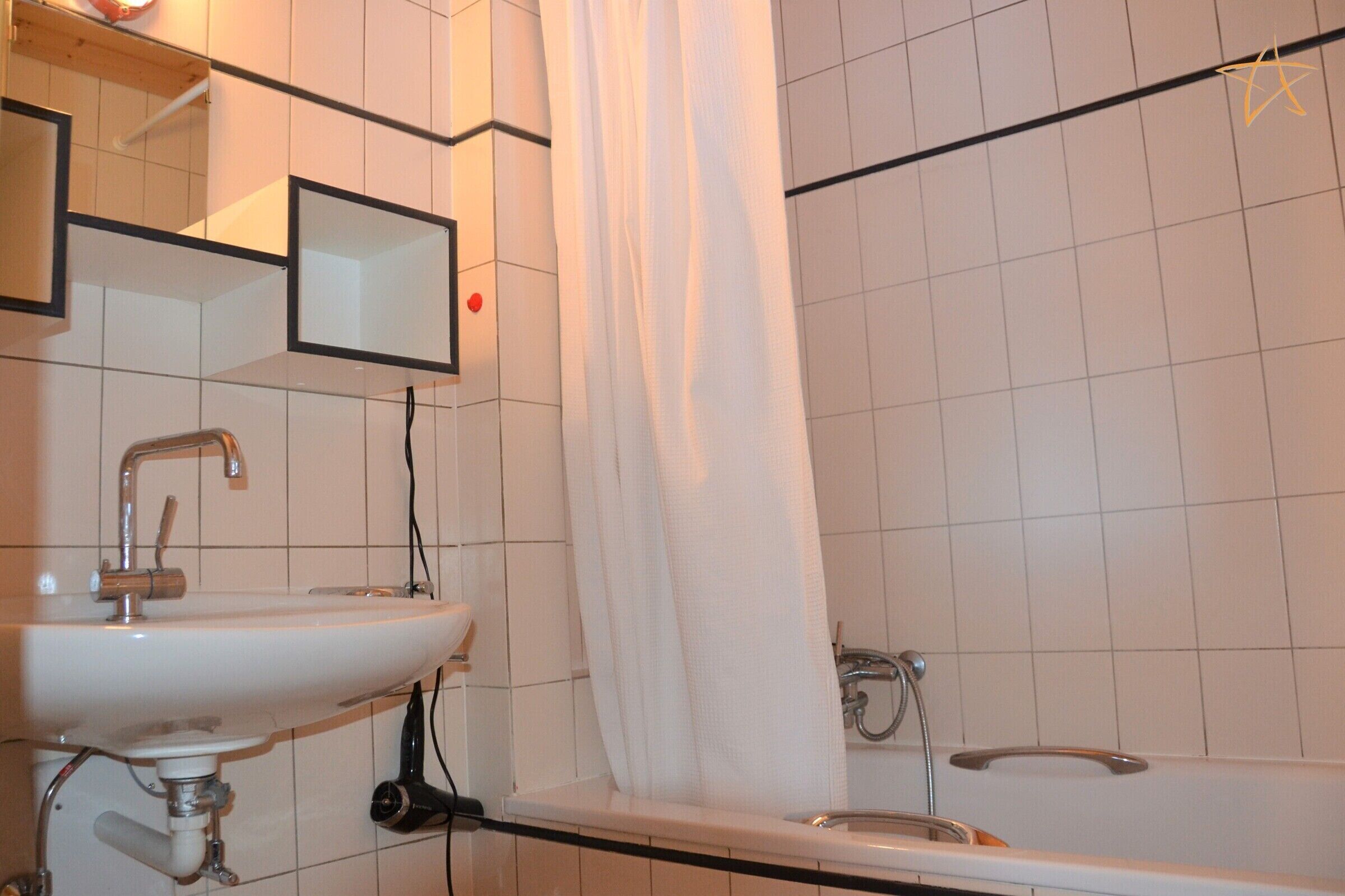 Une salle de bain avec un lavabo blanc, un miroir, un rideau de douche et une baignoire.