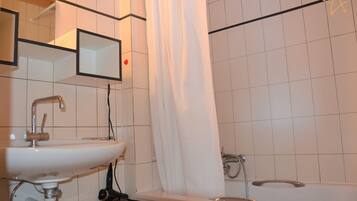 Une salle de bain avec un lavabo blanc, un miroir, un rideau de douche et une baignoire.