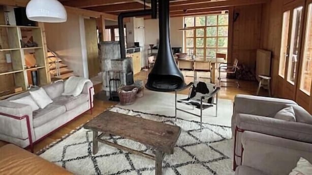 Un interior rústico con chimenea, vigas de madera y un sofá.
