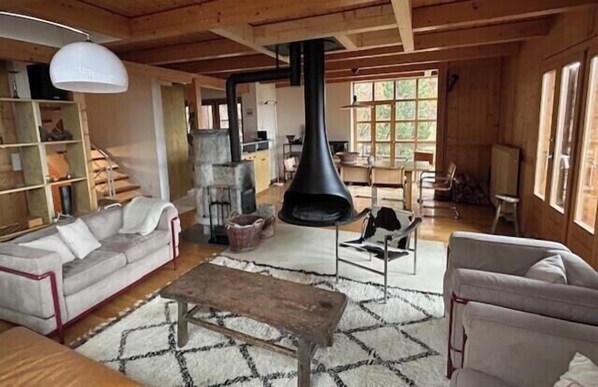A rustic interior with a fireplace, wooden beams, and a sofa.