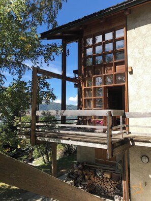 A wooden cabin with a balcony overlooking a mountainous landscape.