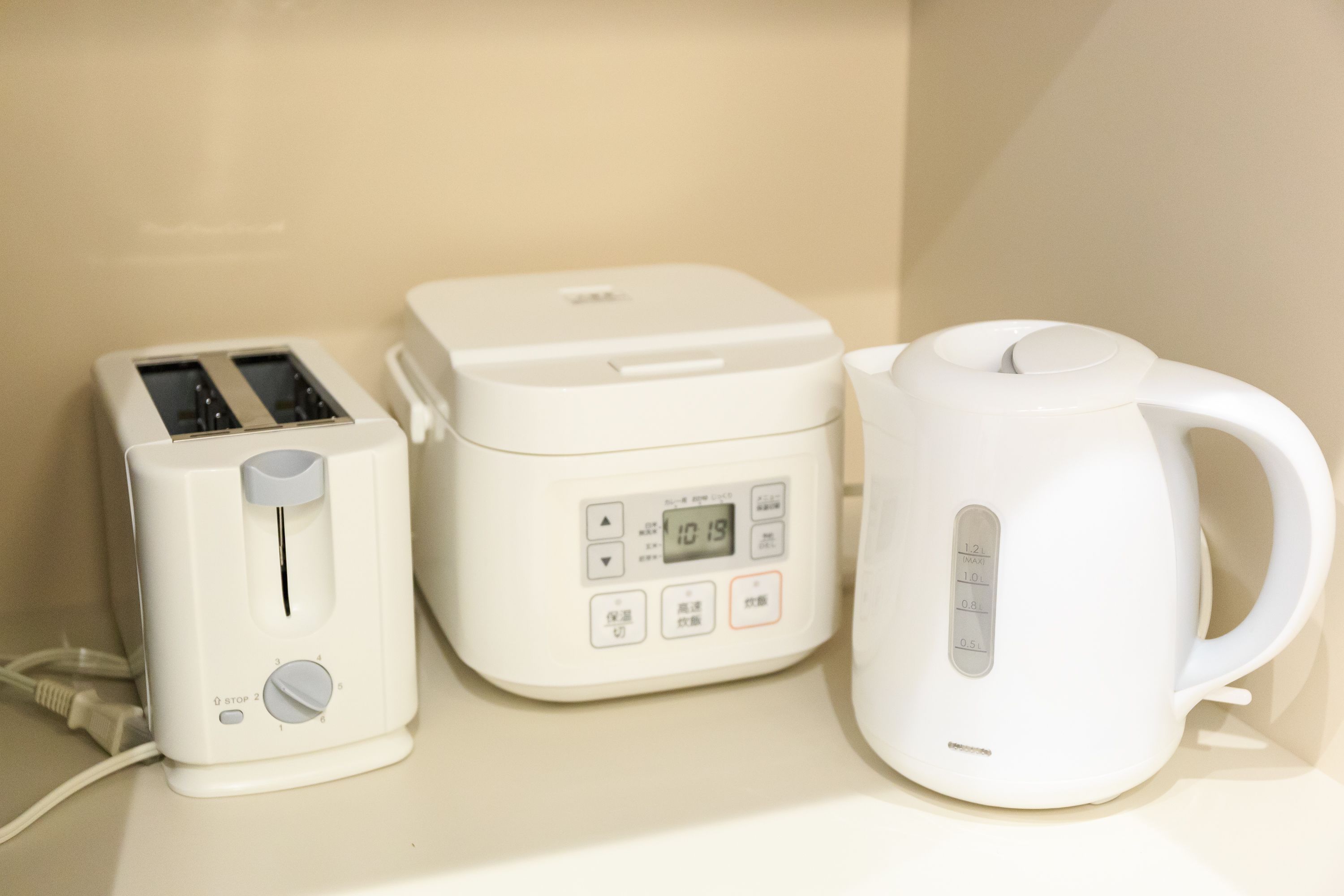 A kitchen with a toaster, a rice cooker, and a kettle.