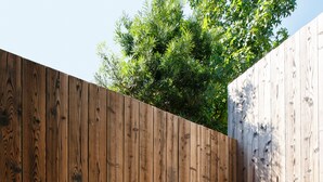 A wooden fence with a gravel path and large rocks.