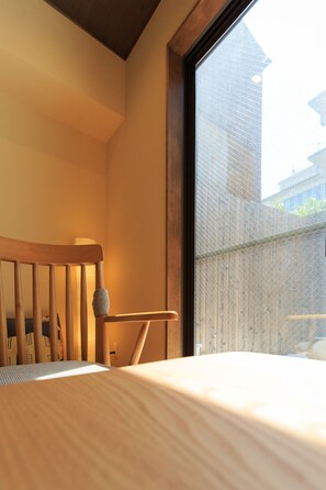 A bedroom with a wooden headboard, a window with a view of buildings, and a bedside lamp. - Kanazawa no yado Ikedaya (Kanazawa)