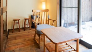 A wooden dining area with a table and chairs, a bench, and a large window with a view of a wooden fence.