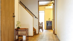 A hallway with wooden flooring, a wooden door, a staircase, and a small table with a plant.
