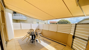 Un patio coperto con tavolo e sedie, un tappeto decorato e un ingresso delimitato da un cancello.
