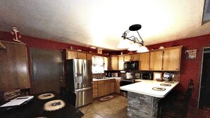 Una cocina con armarios de madera, un refrigerador de acero inoxidable, un microondas y una isla de piedra.