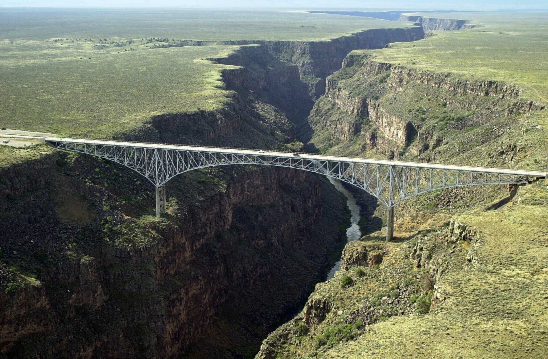 Een brug over een diepe kloof, met een rivier eronder.