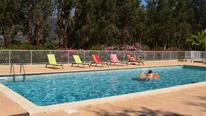 Una piscina con sillas de descanso y una valla.