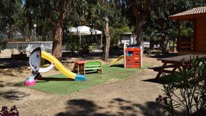 Un parque infantil con tobogán, estructura para escalar y una mesa de picnic.